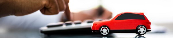 An individual using a calculator with a red car on the desk